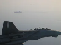 RIPPER 207 (BuNo 161437) over USS George Washington, with a smaller ship in the distance.