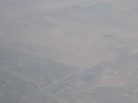 Agricultural/desert terrain with roads, canals and probable airfield/runway complex in haze