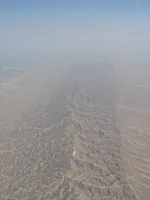 Rugged mountain ridges with river valley and cultivated land beyond