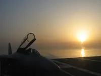 AG-101 F-14 Tomcat cockpit in silhouette on starboard side of landing area on USS George Washington as landings begin