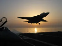 F-14 Tomcat over the ramp on the USS George Washington, silhouetted by the sun in the Persian Gulf