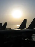 Sun setting in Persian Gulf onboard USS George Washington; Tomcat tails in silhouette