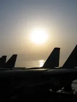 Sun setting in Persian Gulf onboard USS George Washington; Tomcat tails in silhouette