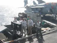 CVW-7 Landing Signal Officers (LSOs) with partial VAQ-140 Patriots Prowler behind them.